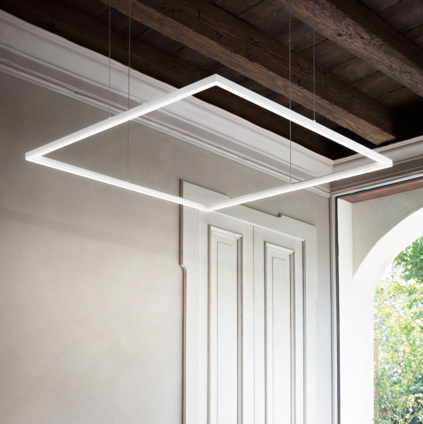 Svietidlo vo forme obdĺžnikového rámu visí zo stropu. Svietidlo je osvetlené. Nachádza sa v interiéri s dreveným stropom a bielymi stenami.