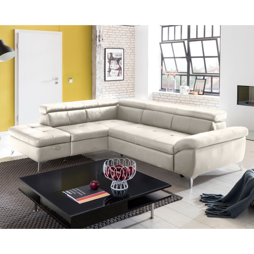 Rohová sedačka svetlohnedej farby stojí na bielom pozadí. Sedačka je rozdelená na tri časti, pričom jedna časť tvorí otoman. Má kovové nožičky.