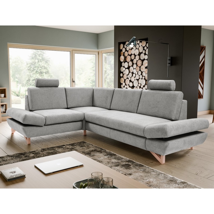 Rohová sedačka svetlošedej farby s drevenými nohami je umiestnená na bielom pozadí. Sedačka má opierky hlavy a je rozdelená do niekoľkých častí.