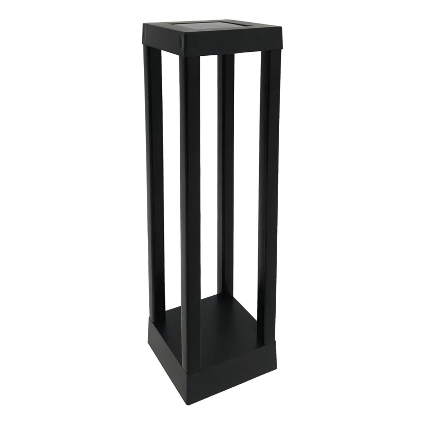 Solárny svietiaci stĺpik stojí na bielom pozadí. Je čierny, vysoký a má štvorcovú základňu a vrch s integrovaným solárnym panelom. Stĺpik je tvorený štyrmi vertikálnymi hranami a jednou vodorovnou priečkou v strede.